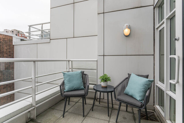 Furnished balcony with modern furniture, light teal cushions, and a sleek wall-mounted light. - THA - 1199 Marinaside Cres, Vancouver Downtown