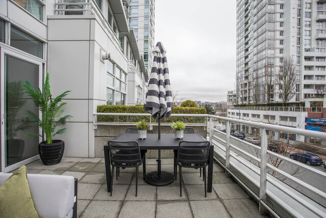 Furnished patio with modern furniture, city view, and striped umbrella. - THA - 1199 Marinaside Cres, Vancouver Downtown