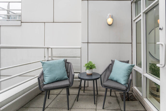 Furnished balcony with modern chairs, teal cushions, and a small potted plant. - THA - 1199 Marinaside Cres, Vancouver Downtown