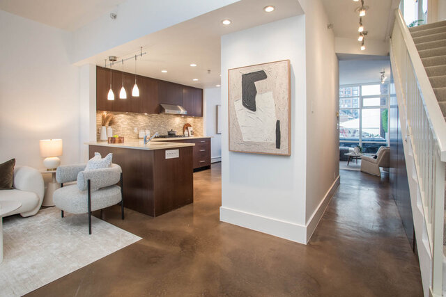Open-concept living with concrete floors, modern kitchen, and city view. - THA - 1199 Marinaside Cres, Vancouver Downtown