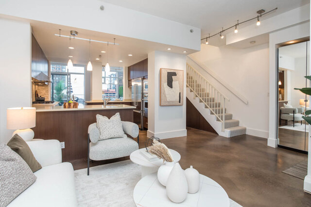 Open-concept living space with modern decor, featuring a kitchen island and a cozy living area with a white sofa.