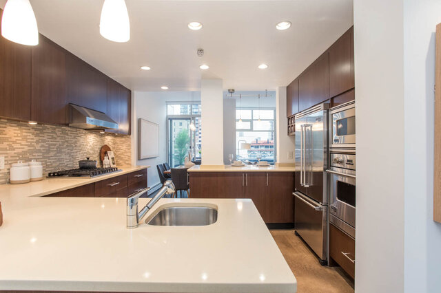 Modern kitchen with sleek countertops and stainless steel appliances, featuring a city view. - THA - 1199 Marinaside Cres, Vancouver Downtown