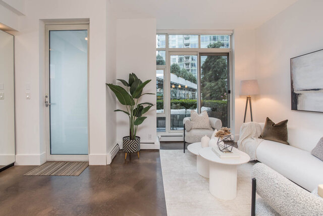 Spacious living room with modern furniture, large windows, and a city view. - THA - 1199 Marinaside Cres, Vancouver Downtown