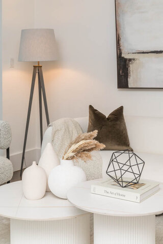 Spacious living room with modern decor, featuring a sleek white coffee table, a geometric black sculpture, and a cozy...
