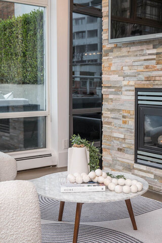 Cozy living room with stone fireplace, marble coffee table, and city view. - THA - 1199 Marinaside Cres, Vancouver Downtown