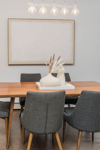 Modern dining room with sleek wooden table, gray upholstered chairs, and abstract art above. - THA - 1199 Marinaside Cres, Vancouver Downtown