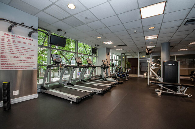 Spacious fitness center with treadmills, windows, and city views. - THA - 1199 Marinaside Cres, Vancouver Downtown
