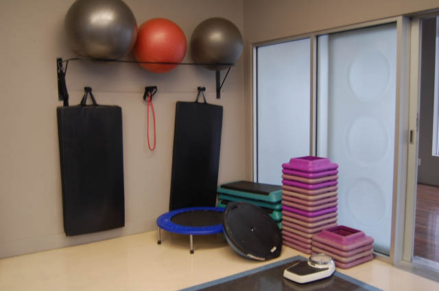 Spacious fitness room with exercise equipment, including weights and mats, and sliding glass doors leading to a private...