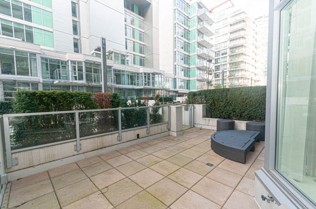 Furnished balcony with glass railings and city views. - 105 - 199 Victory Ship Way, North Vancouver