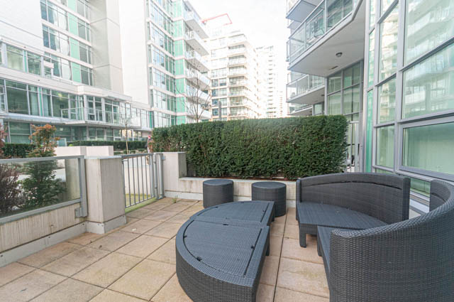 Furnished patio with outdoor seating and hedge privacy. - 105 - 199 Victory Ship Way, North Vancouver