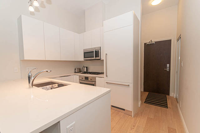 Bright kitchen with white countertops and hardwood floors. - 105 - 199 Victory Ship Way, North Vancouver