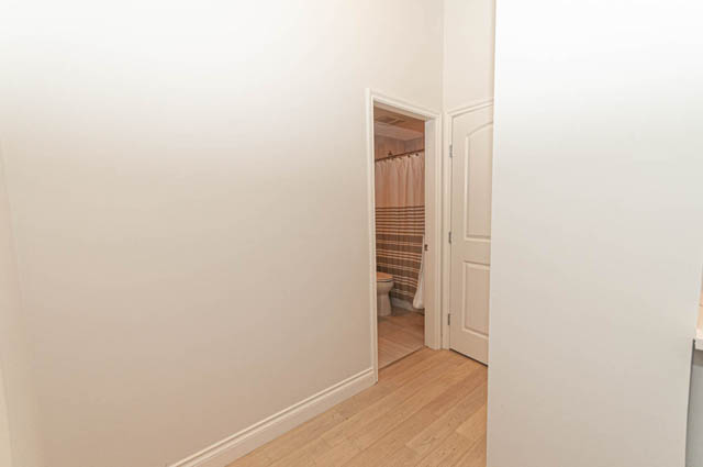 Furnished hallway with wooden flooring and closet doors. - 105 - 199 Victory Ship Way, North Vancouver