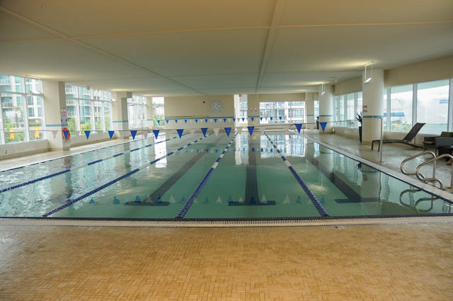 Spacious indoor pool with blue lane dividers and tiled deck. - 105 - 199 Victory Ship Way, North Vancouver