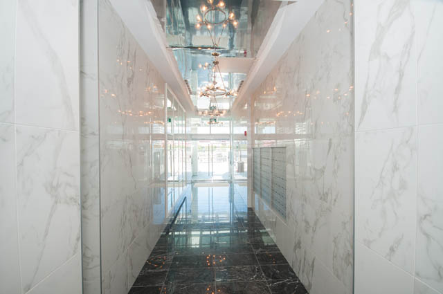 Spacious living room with marble walls and floor, modern chandelier. - 105 - 199 Victory Ship Way, North Vancouver