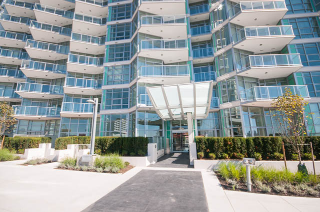Modern 1-bedroom condo with sleek glass facade and balcony access. - 105 - 199 Victory Ship Way, North Vancouver
