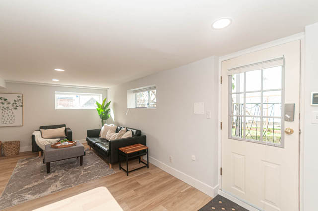 Bright living room with hardwood floors, modern furniture, and large windows. - Suite - 522 5th St E, North Vancouver