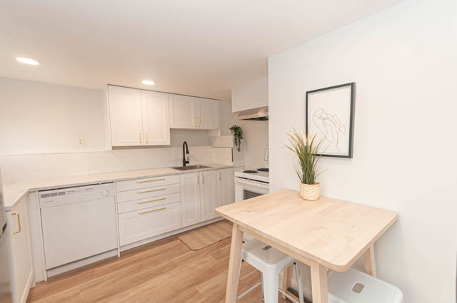 Bright kitchen with white cabinetry, hardwood floors, and a modern island. - Suite - 522 5th St E, North Vancouver
