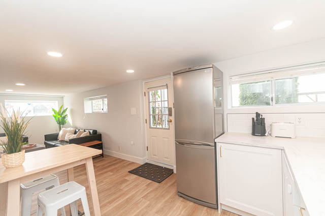 Bright kitchen with white countertops, hardwood floors, and a city view. - Suite - 522 5th St E, North Vancouver