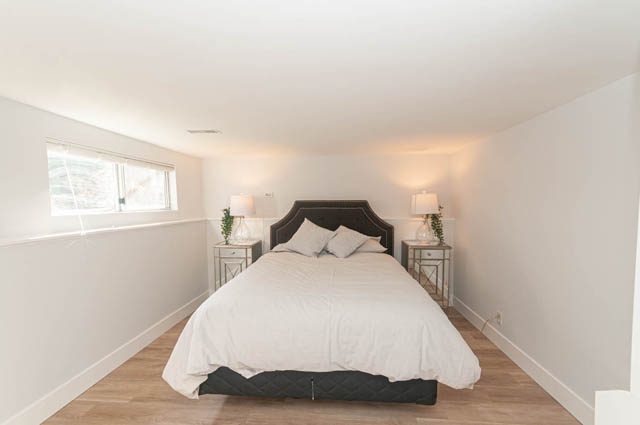 Bright bedroom with hardwood floors and a large window, showcasing a serene and modern ambiance. - Suite - 522 5th St E, North Vancouver