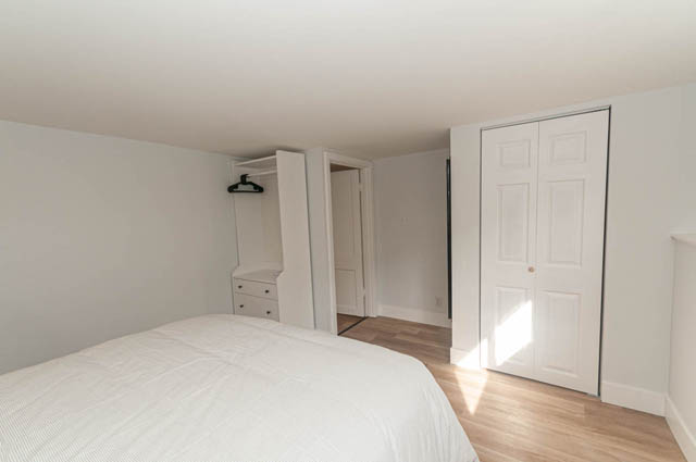 Furnished 1-bedroom + den suite with white walls, built-in closet, and hardwood floors. - Suite - 522 5th St E, North Vancouver