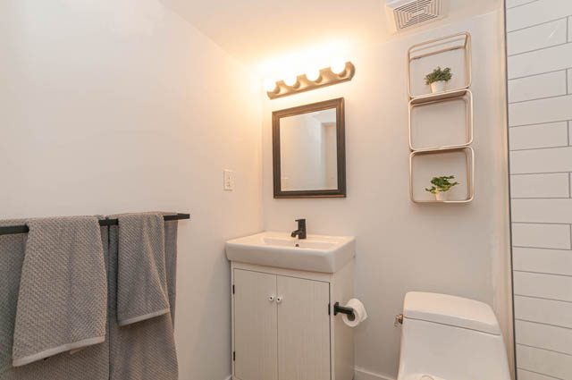 Bright bathroom with white subway tiles and a modern shelf design. - Suite - 522 5th St E, North Vancouver