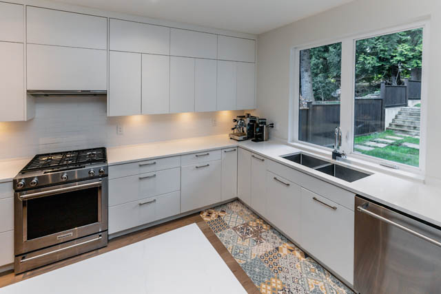 Bright kitchen with white cabinets, granite countertops, and a view of the backyard. - Address WITHHELD, North Vancouver