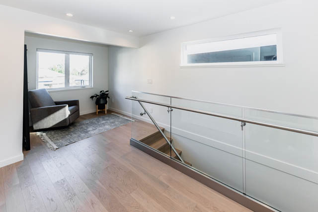 Bright living room with hardwood floors and a modern staircase leading to the upper level. - Address WITHHELD, North Vancouver