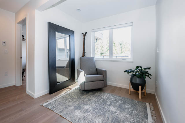 Bright living room with hardwood floors and a large window, showcasing a serene outdoor view. - Address WITHHELD, North Vancouver