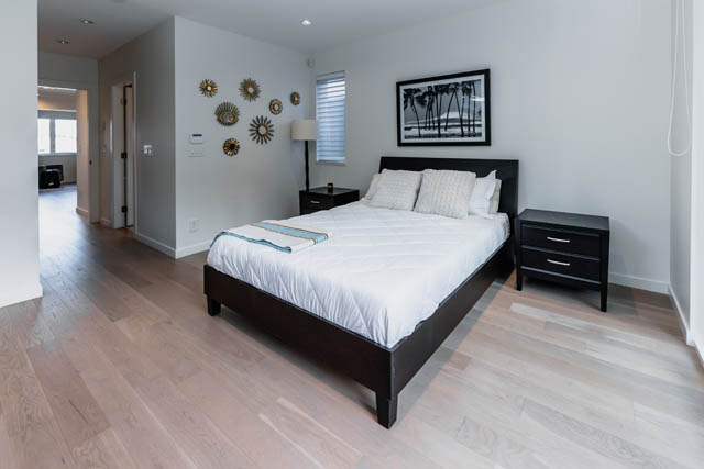 Bright bedroom with hardwood floors, modern decor, and a cozy bed setup. - Address WITHHELD, North Vancouver