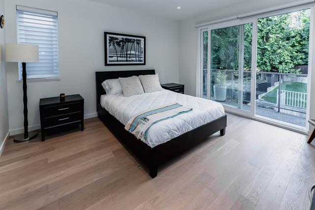 Spacious bedroom with hardwood floors, large sliding glass doors, and a serene garden view. - Address WITHHELD, North Vancouver