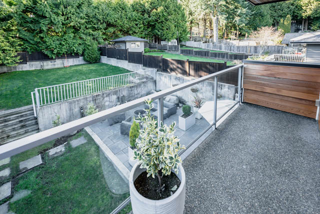Bright patio with modern railings and potted plants, surrounded by lush greenery. - Address WITHHELD, North Vancouver