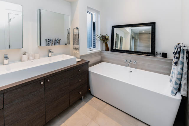 Modern bathroom with dark wood cabinets and a large mirror. - Address WITHHELD, North Vancouver