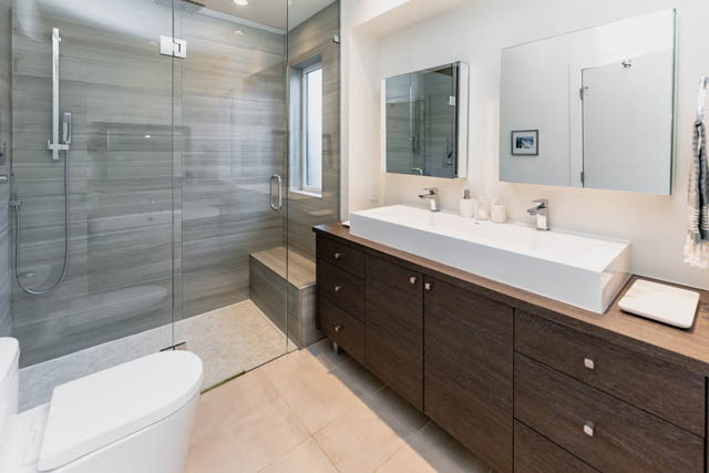 Modern bathroom with white vessel sinks, dark wood cabinets, and a glass shower enclosure. - Address WITHHELD, North Vancouver