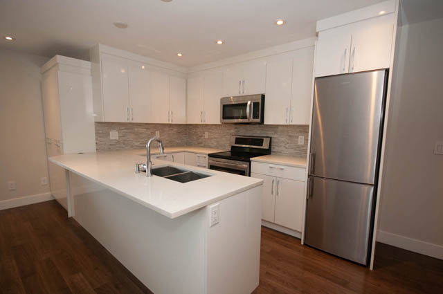 Bright kitchen with white cabinets, stainless steel appliances, and hardwood floors. - Suite - 4796 Skyline Dr, North Vancouver