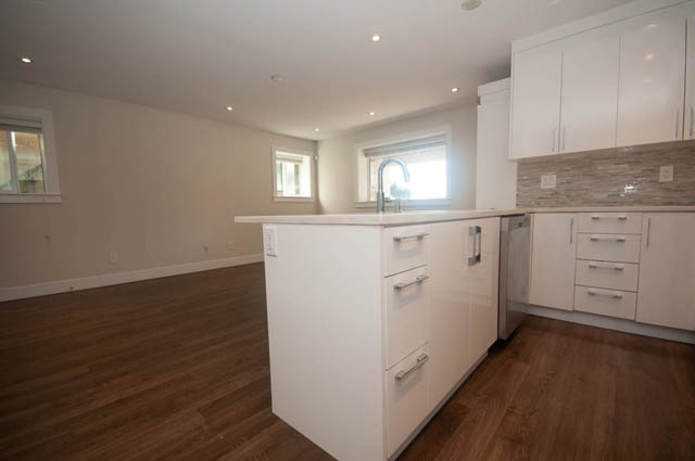 Bright kitchen with white cabinets, hardwood floors, and a window view. - Suite - 4796 Skyline Dr, North Vancouver