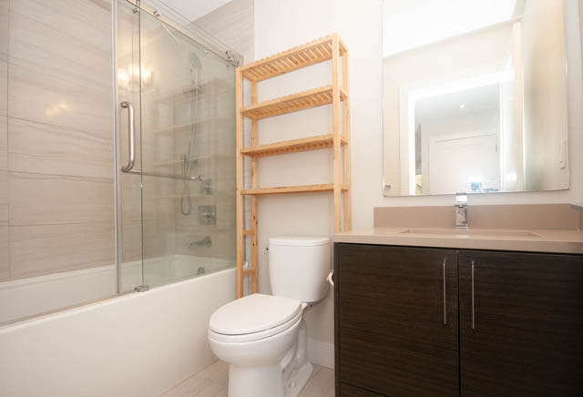 Bright bathroom with modern fixtures and wooden shelving. - Suite - 4796 Skyline Dr, North Vancouver
