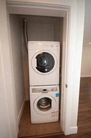 Laundry room with stacked washer and dryer, hardwood floors. - Suite - 4796 Skyline Dr, North Vancouver