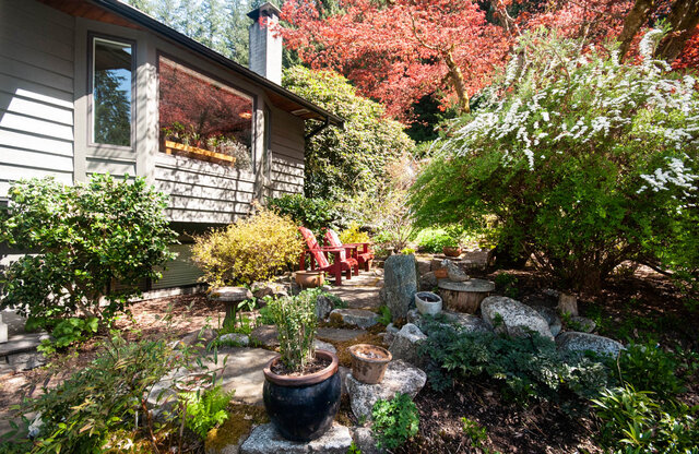 Cozy patio with red Adirondack chairs and vibrant fall foliage, perfect for relaxing. - Upper - 2352 Riverbank Pl, North Vancouver
