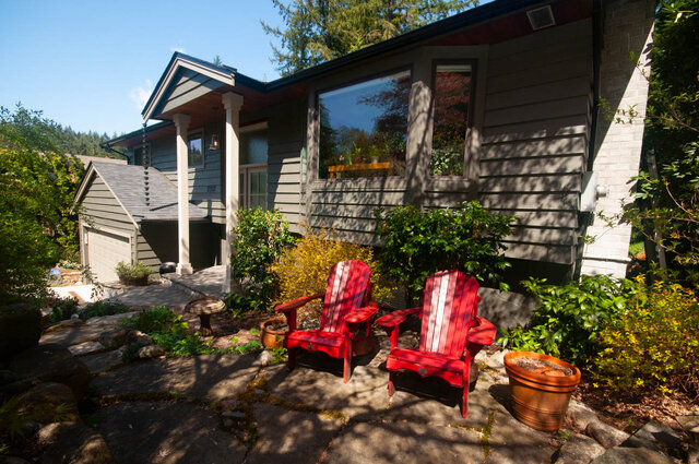Cozy patio with red Adirondack chairs and lush greenery, perfect for relaxation. - Upper - 2352 Riverbank Pl, North Vancouver