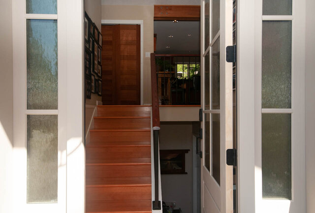 Staircase leading to upper level with wooden banister and framed artwork on wall. - Upper - 2352 Riverbank Pl, North Vancouver