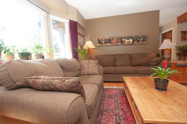 Spacious living room with plush sofas, wooden coffee table, and vibrant wall art. - Upper - 2352 Riverbank Pl, North Vancouver