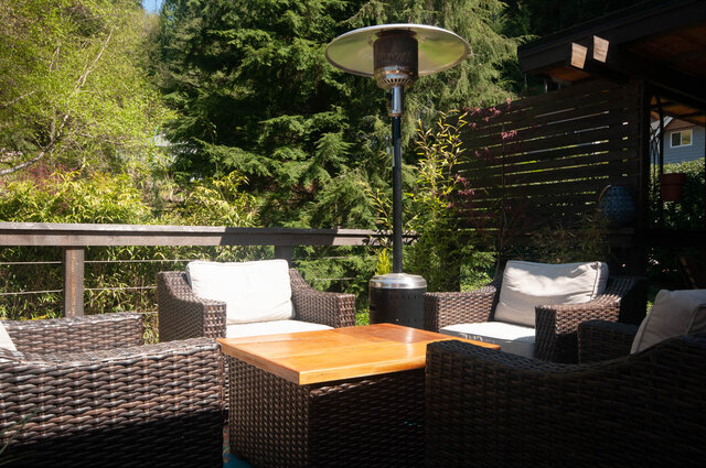 Furnished patio with wicker furniture, a tall patio heater, and lush greenery in the background. - Upper - 2352 Riverbank Pl, North Vancouver