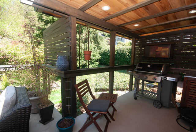 Covered patio with wooden pergola, outdoor grill, and cozy seating area. - Upper - 2352 Riverbank Pl, North Vancouver