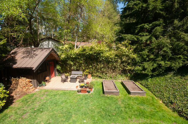 Spacious backyard with lush greenery, raised garden beds, and a cozy outdoor seating area. - Upper - 2352 Riverbank Pl, North Vancouver
