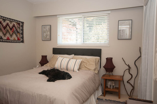 Spacious bedroom with a cozy bed, neutral decor, and a window with blinds. - Upper - 2352 Riverbank Pl, North Vancouver