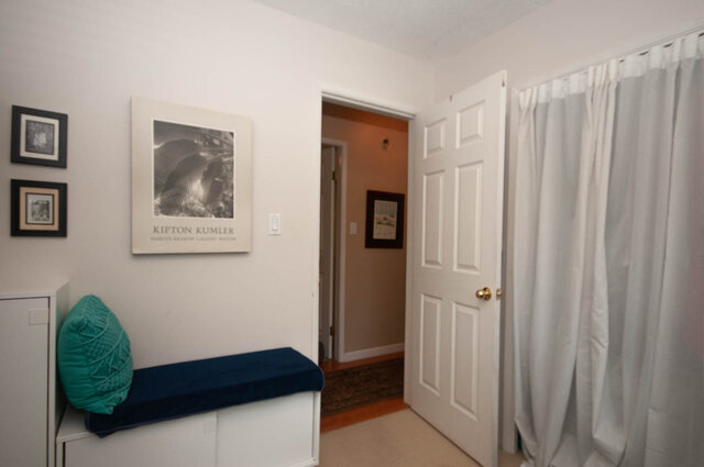 Furnished bedroom with white walls, framed art, and a cozy blue bench. - Upper - 2352 Riverbank Pl, North Vancouver