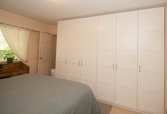Spacious bedroom with large white closet and wooden dresser, perfect for a cozy stay. - Upper - 2352 Riverbank Pl, North Vancouver