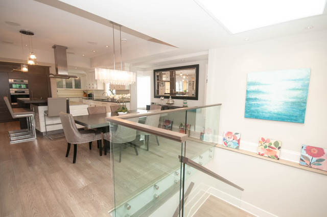 Modern kitchen with glass countertop and hardwood floors. - Upper - 876 48th Ave, Vancouver West Side