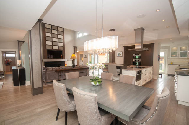 Bright kitchen with hardwood floors and modern lighting, open to a dining area. - Upper - 876 48th Ave, Vancouver West Side