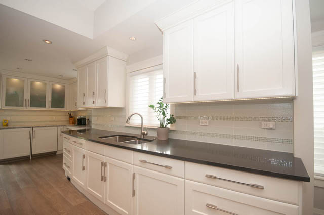 Bright kitchen with white cabinets, granite countertops, and hardwood floors. - Upper - 876 48th Ave, Vancouver West Side
